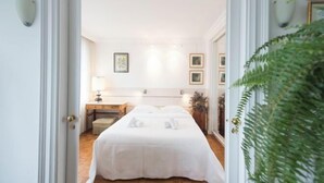 A hotel room with a bed, bedside tables, a desk, and a lamp.