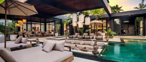 A modern outdoor lounge area with a pool, seating arrangements, and ambient lighting.