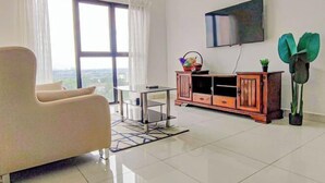 Een moderne woonkamer met een bank, een televisie, een kast en een groot raam.