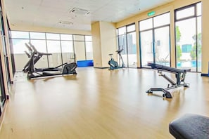 Une salle de sport équipée de matériel d’exercice, dotée de grandes fenêtres et d’un plancher en bois.