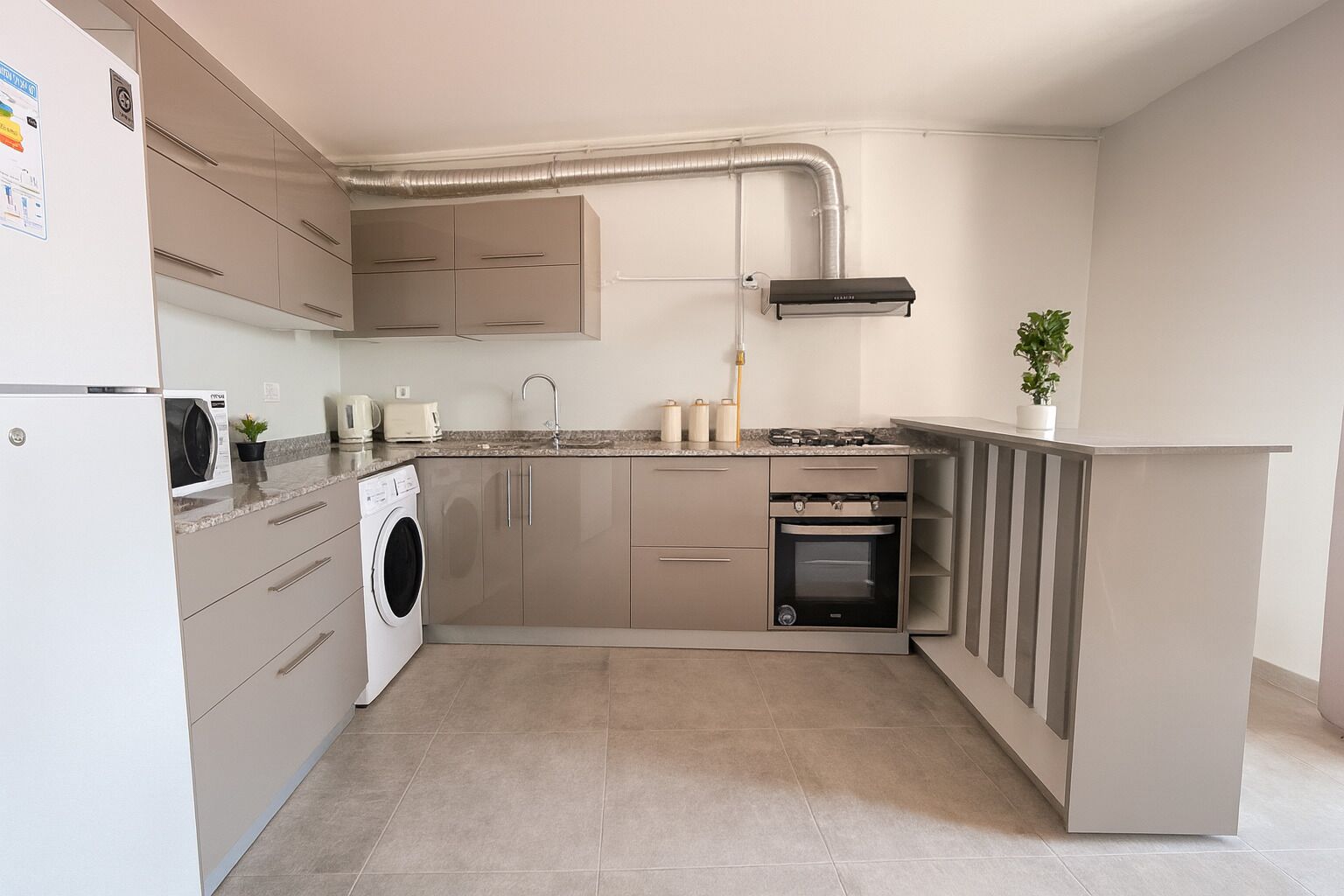 Eine kleine Küche mit Waschmaschine, Backofen und integriertem Herd.