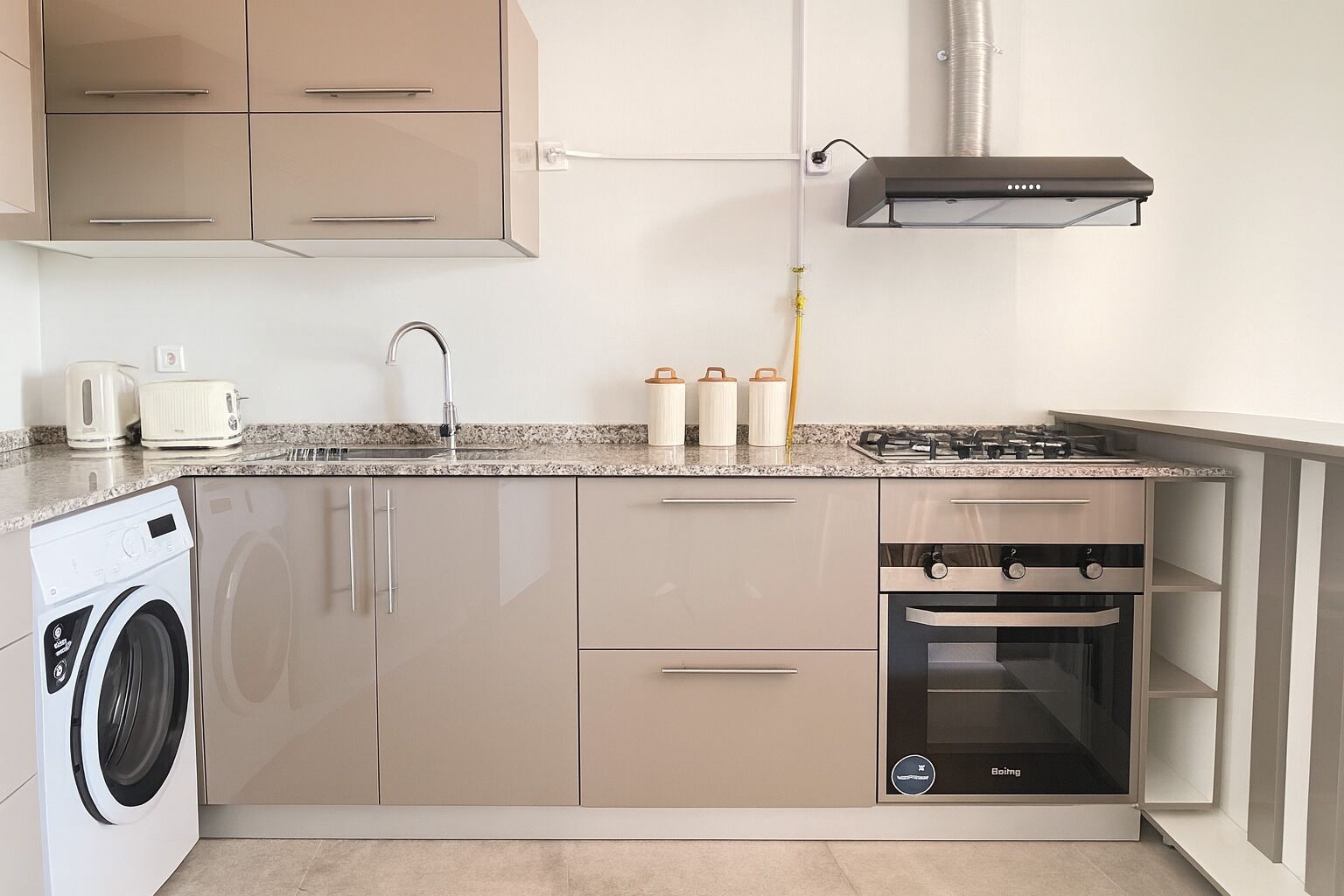 A compact kitchen with a washing machine, a built-in oven, and a gas stove.