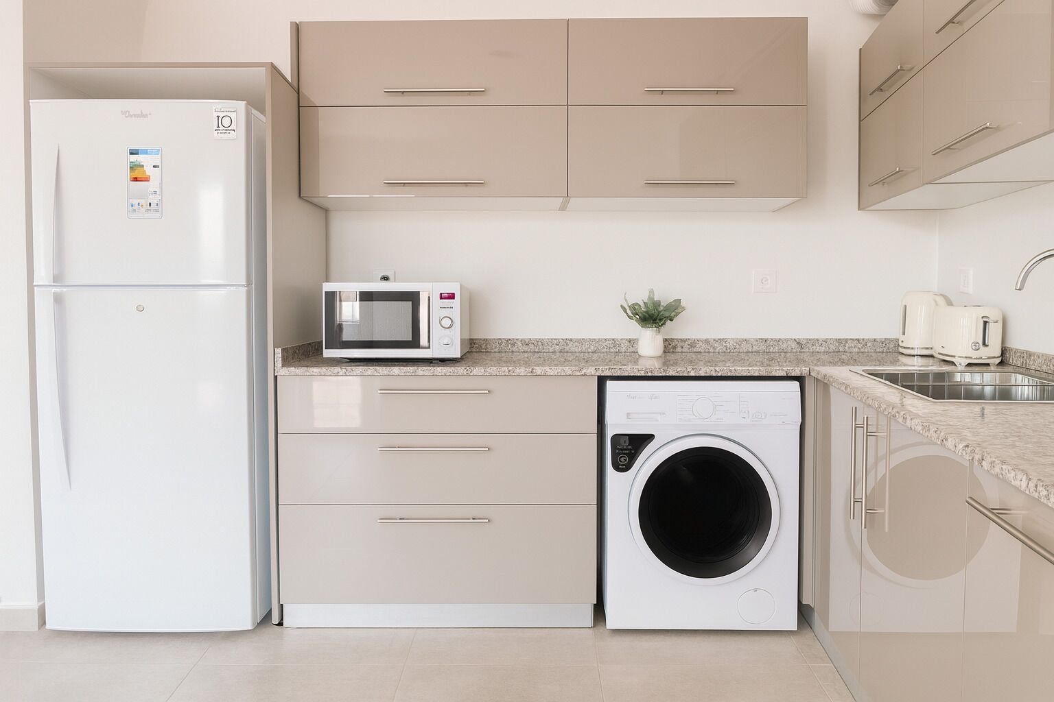 A compact kitchen with a refrigerator, microwave, and washing machine.