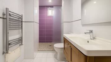 Un bagno moderno con un lavandino bianco, un rubinetto cromato e una doccia con un porta asciugamani cromato.