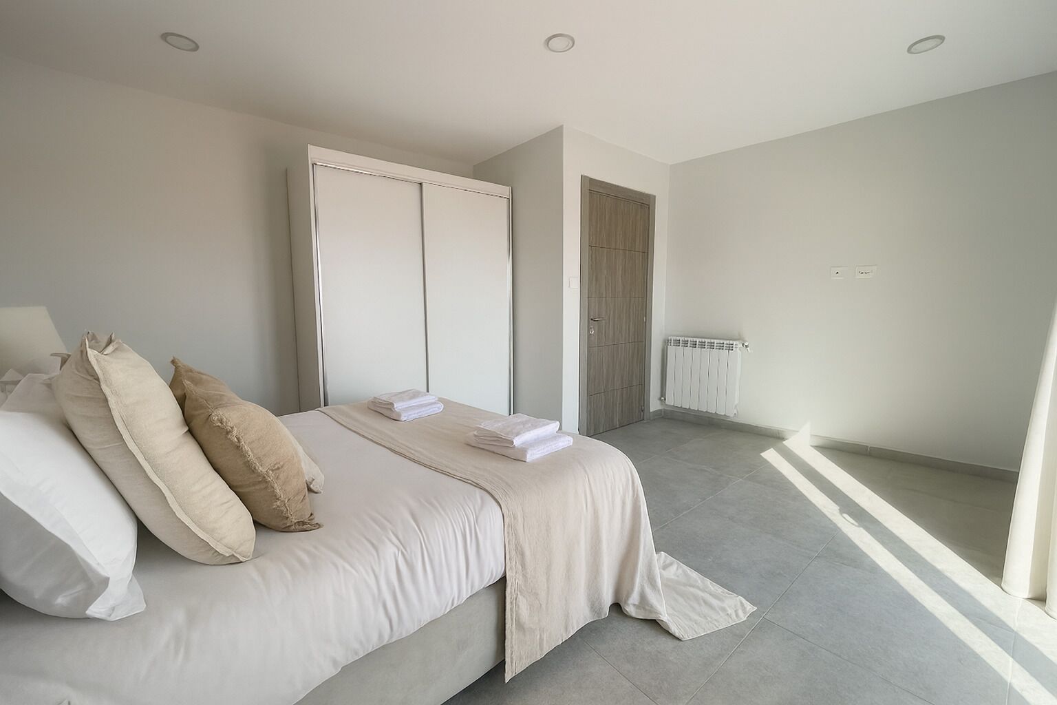 Een moderne slaapkamer met een groot bed, een kledingkast en een radiator.