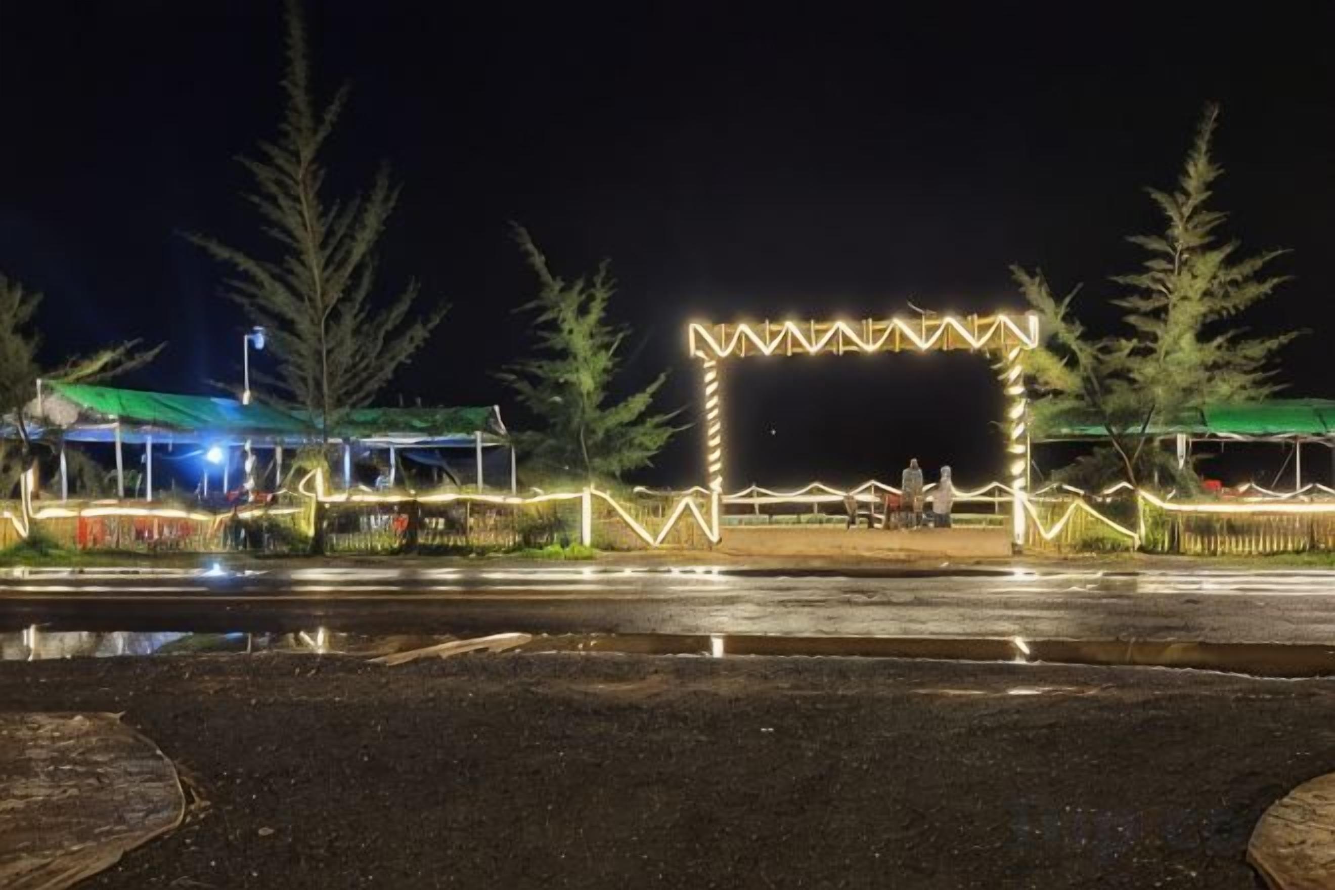 Une vue nocturne d’un parking avec une structure illuminée qui ressemble à une porte ou à une arche.