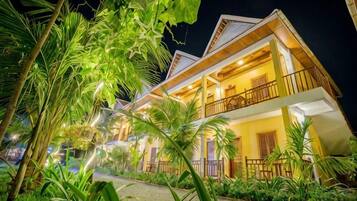Un edificio de dos plantas con balcones, rodeado de vegetación tropical.