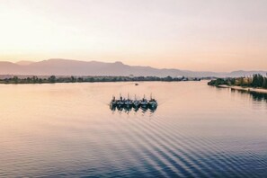 A calm river with a group of boats anchored in the middle. - NanaSky Kampot Residence (Kampot)