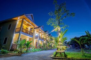 A multi-story hotel with balconies, a well-lit entrance, and a landscaped garden. - NanaSky Kampot Residence (Kampot)