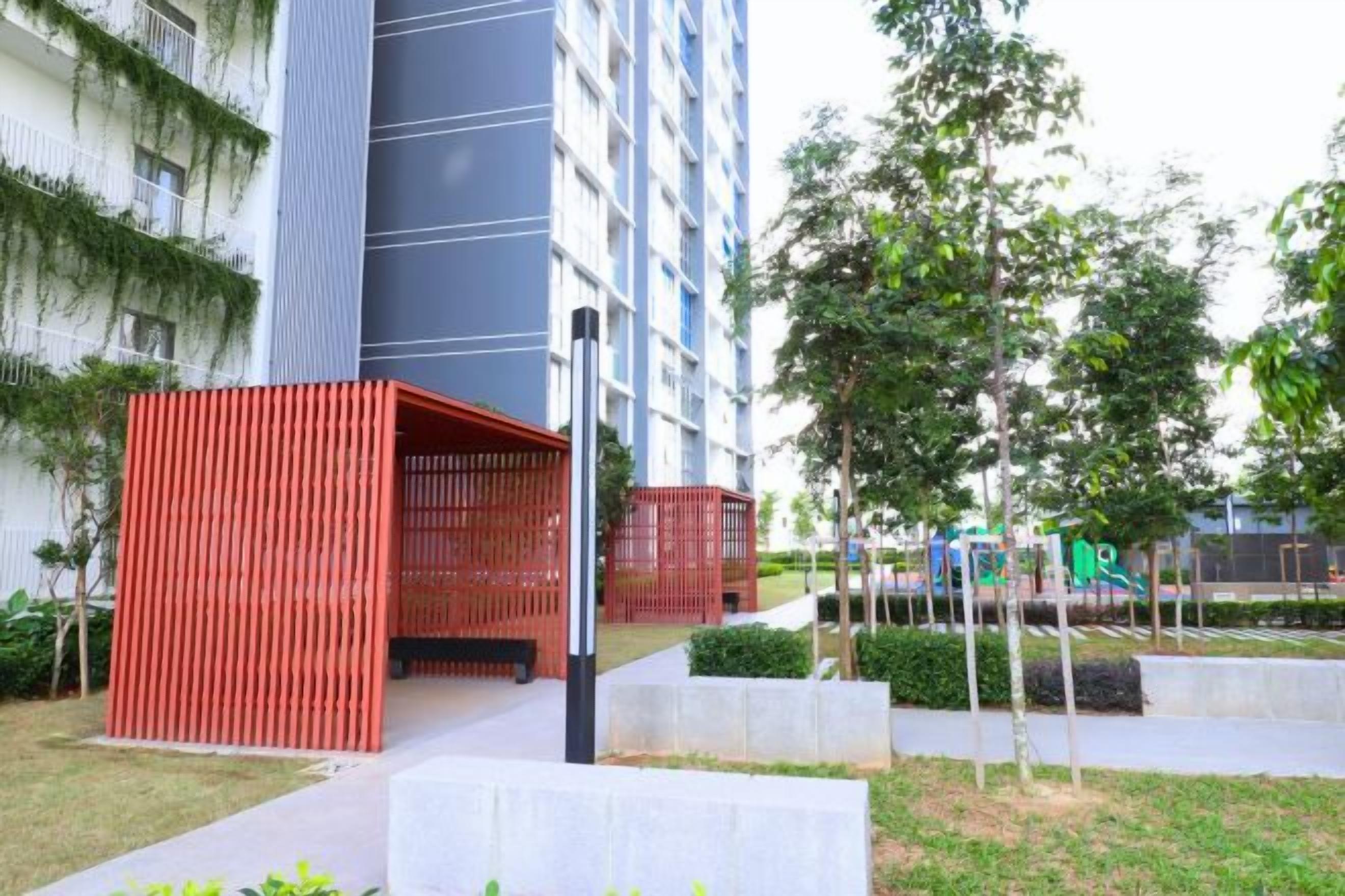 Un edificio moderno con una estructura roja, un camino y vegetación.