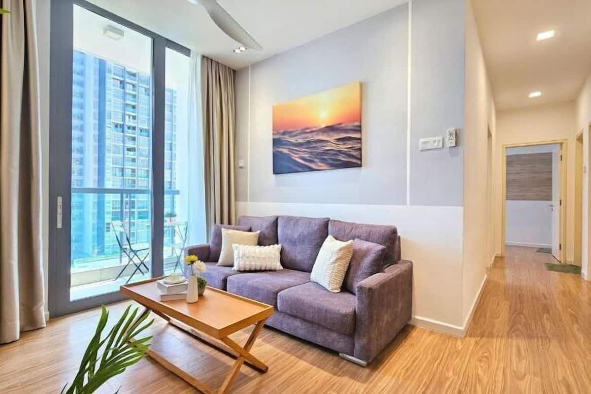 A modern living room with a sofa, a coffee table, and a painting of a sunset.