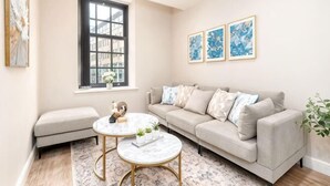 A living room with a sofa, two round tables, a window, and framed artwork on the wall. - Beautiful Retreat in the Heart of the City Leeds (Leeds)