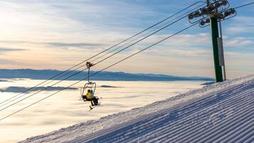 A ski lift with passengers, a snowy mountain slope, and a clear sky.