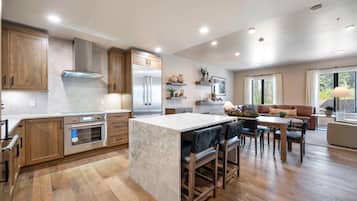 Een moderne keuken met houten kastjes, roestvrijstalen apparatuur en een marmeren eiland.