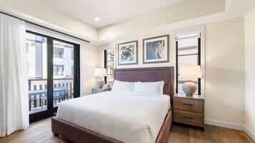 A hotel room with a large bed, a balcony, and two bedside tables with lamps.