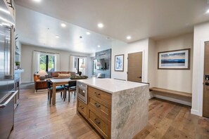 Una cocina moderna con una isla central, armarios de madera y un comedor con mesa y sillas.