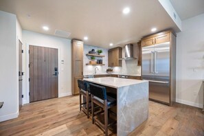 Une cuisine moderne dotée d’un îlot central, de meubles en bois et d’appareils électroménagers en acier inoxydable.