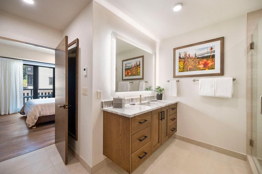 Un baño moderno con un espejo grande, armarios de madera y una zona de ducha.