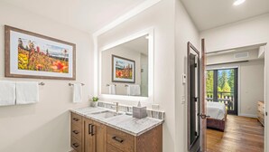 Une salle de bain moderne avec un meuble-lavabo à deux vasques, un grand miroir et un tableau représentant un paysage, encadré.