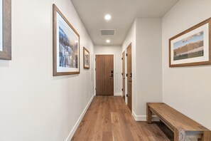 Un pasillo con suelo de madera, cuadros en las paredes y un banco.
