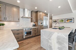 Una cocina moderna con armarios de madera, electrodomésticos de acero inoxidable y una isla de encimera de mármol.