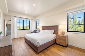A bedroom with a large bed, two bedside tables, a nightstand, a desk, and a chair.