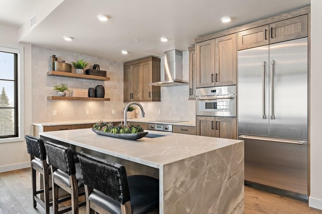 A modern kitchen with a marble island, stainless steel appliances, and wooden cabinets.