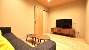 A living room with a sofa, two small tables, a TV on a wooden stand, and a sliding door. - Tamatsukan/Namba 6mins/Universal Studio 37 mins/Tsuruhashi 7mins/Nara30min (Osaka)