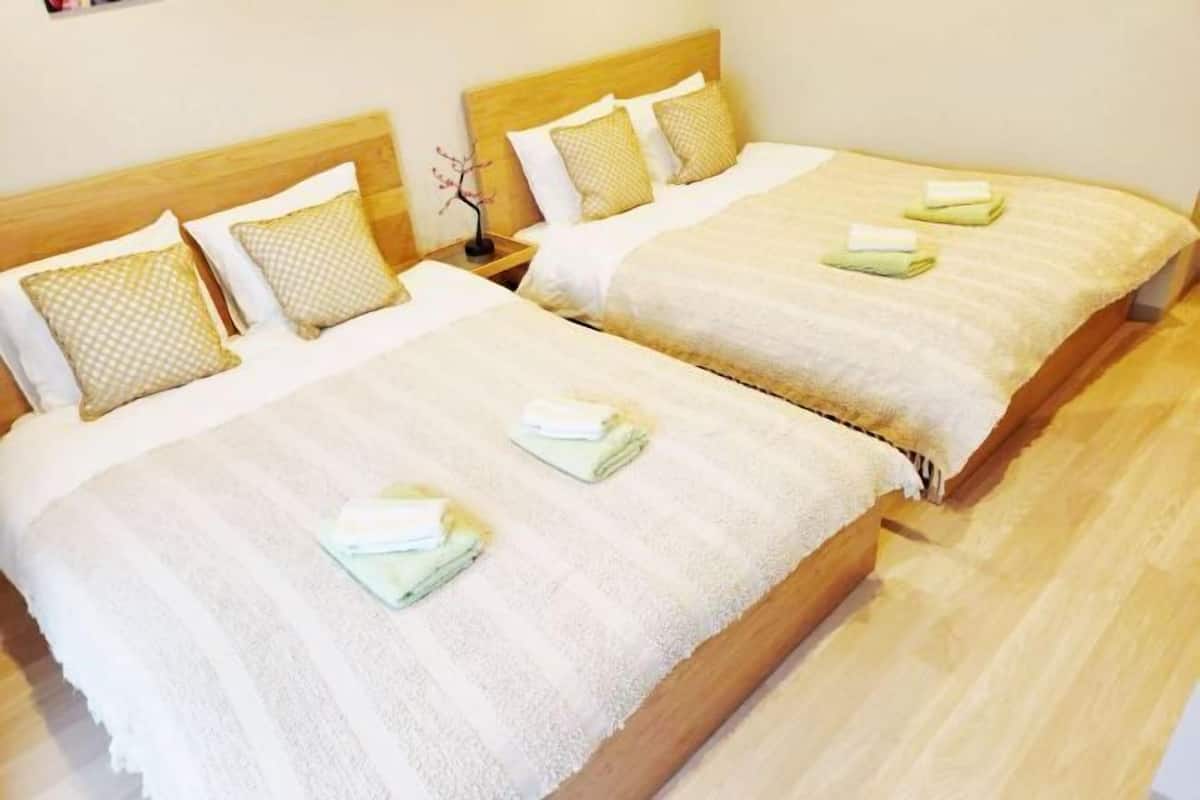 Two double beds with wooden headboards and white bedding, each with a folded towel on the bed.