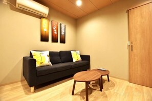 A room with a black sofa, a round wooden table, and a wooden wardrobe. - Tamatsukan/Namba 6mins/Universal Studio 37 mins/Tsuruhashi 7mins/Nara30min (Osaka)