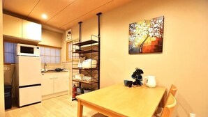 A compact kitchen with a microwave, refrigerator, and wooden dining table. - Tamatsukan/Namba 6mins/Universal Studio 37 mins/Tsuruhashi 7mins/Nara30min (Osaka)