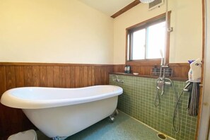 A bathroom with a freestanding bathtub, a window, and a tiled wall. - Poroto Base (Shiraoi)