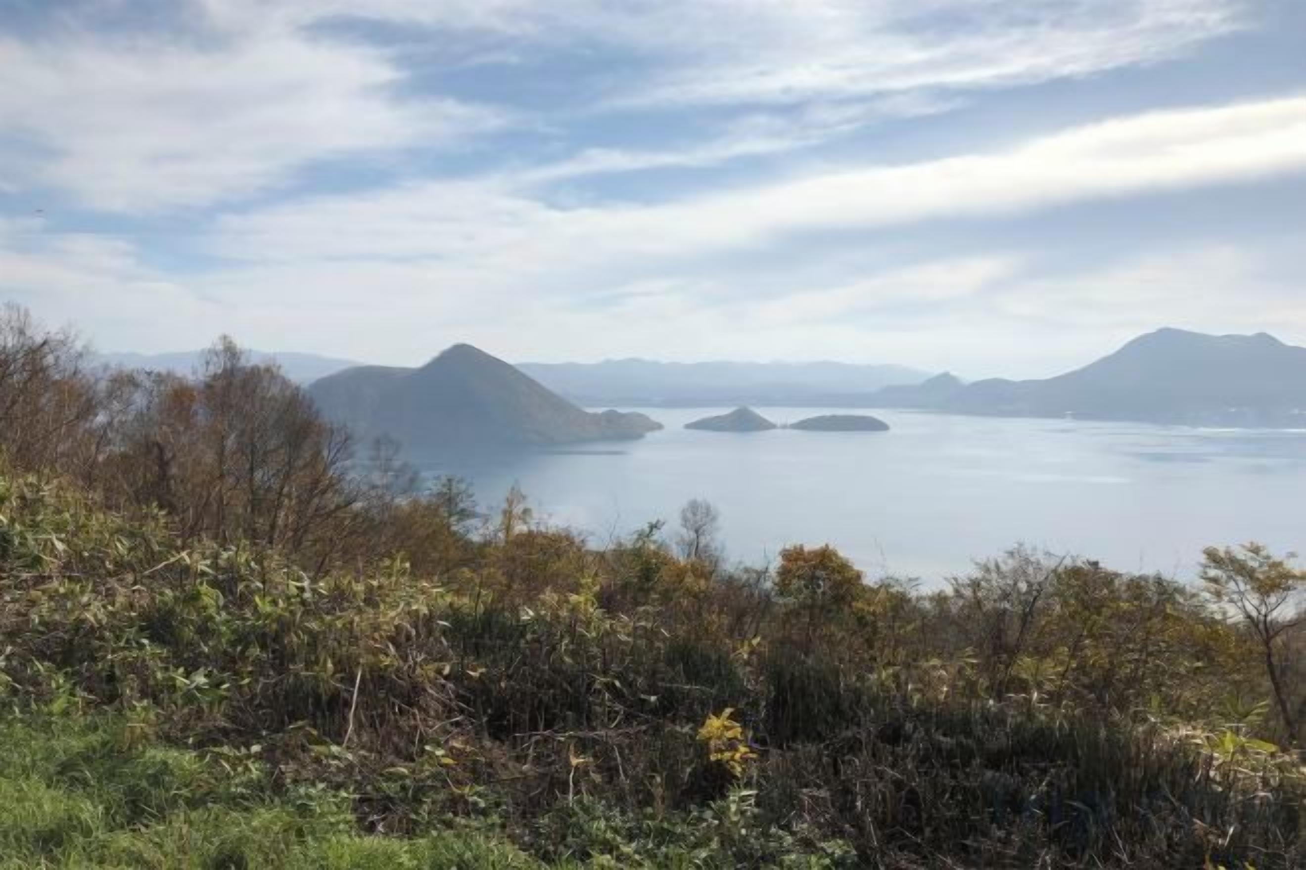 A coastal landscape with mountains and a calm sea.