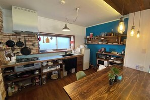 A compact kitchen with a wooden countertop, a built-in stove, and a window with a view. - Poroto Base (Shiraoi)