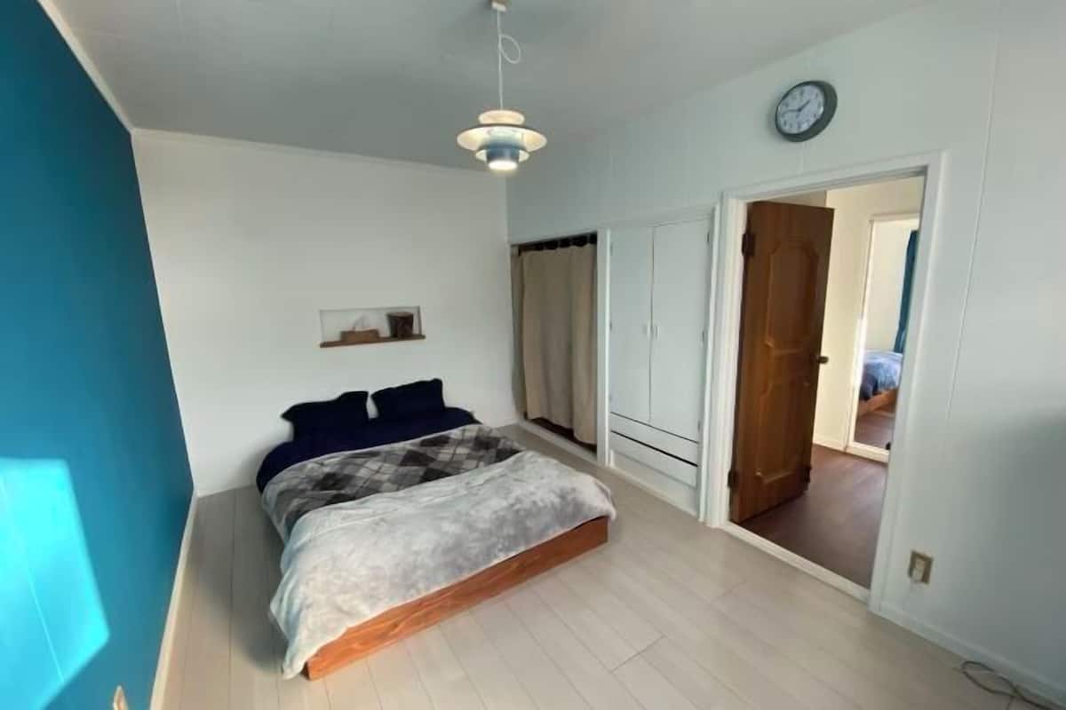 A bedroom with a bed, a ceiling light, a clock, and a wardrobe.