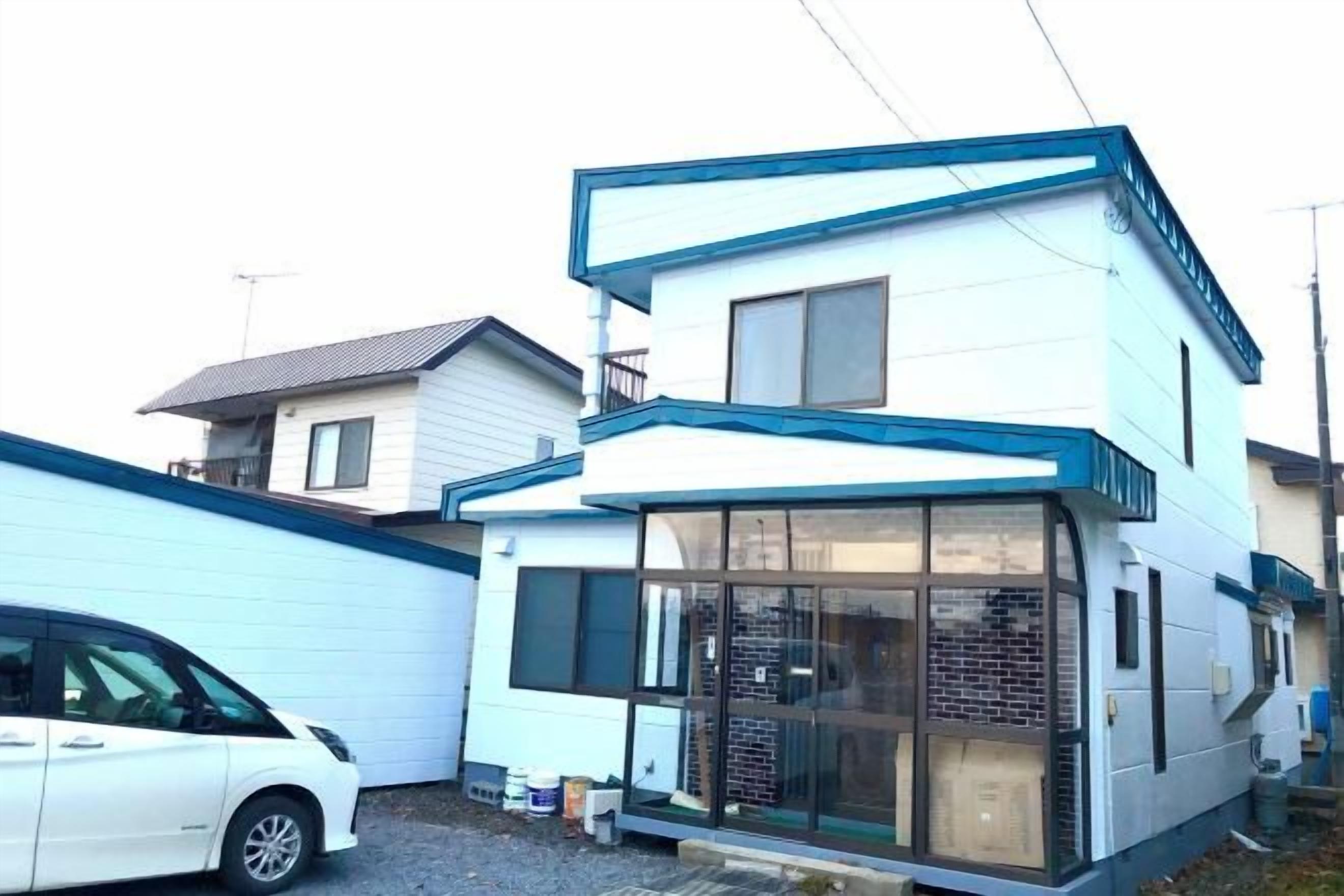 A two-story residential building with a garage and a car parked in front.