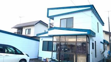 A two-story residential building with a garage and a car parked in front.