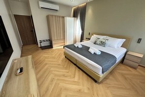 A hotel room with a bed, bedside tables, a wardrobe, and an air conditioning unit. - Naka Central Happy Home in Phuket city (Phuket)