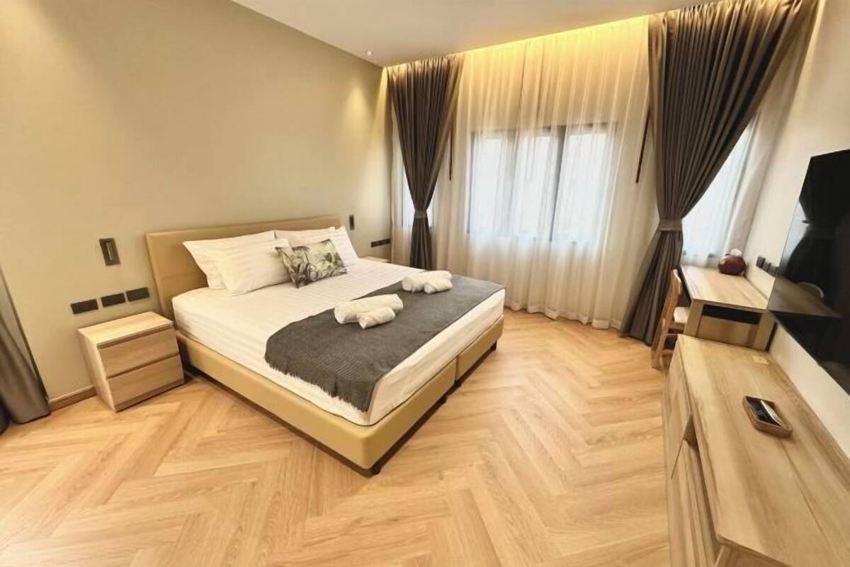 A hotel room with a bed, bedside tables, a TV, and curtains.