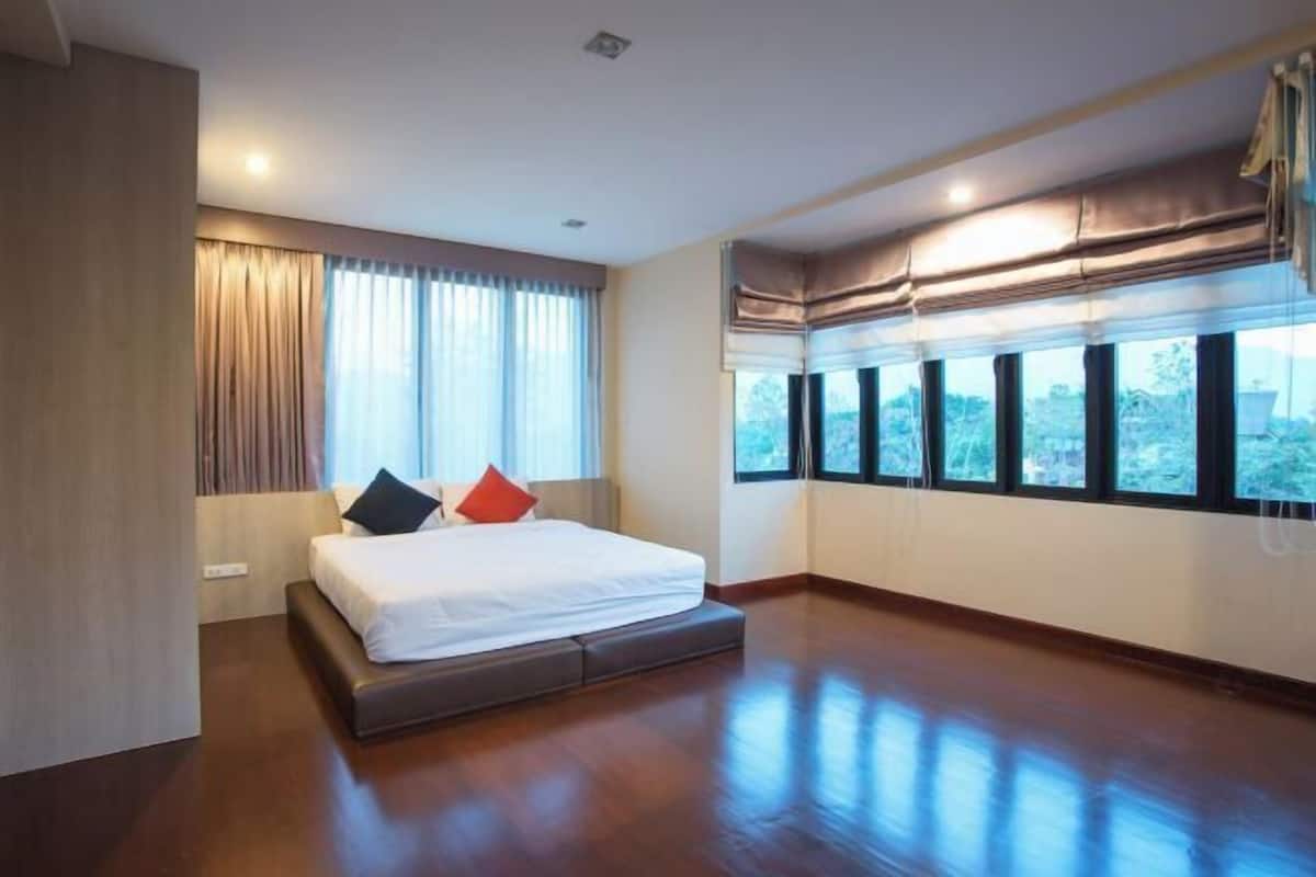 A hotel room with a large bed, a window with a view, and a ceiling fan.