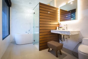 A modern bathroom with a glass shower enclosure, a wooden panel wall, a marble sink, and a white toilet.
