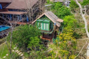 A house surrounded by dense foliage, with a visible swimming pool and a distinct green structure. - Naralin Khaoyai (Pak Chong)