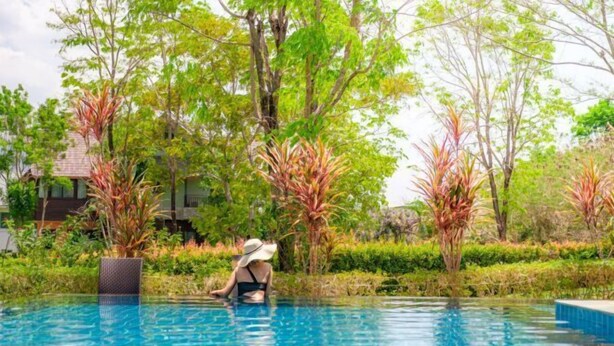 A clear blue pool surrounded by lush greenery and trees. - Naralin Khaoyai (Pak Chong)