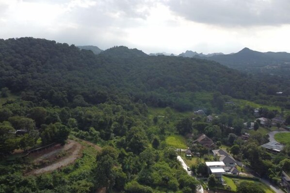 Un paysage montagneux avec une forêt dense, une route sinueuse et des bâtiments dispersés.