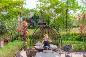 Un jardín con una mecedora de mimbre, una mesa y mobiliario exterior.