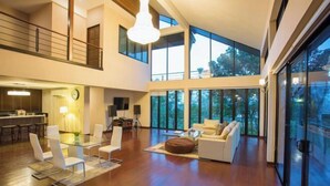 A spacious living area with a glass dining table, white chairs, and a sofa. - Naralin Khaoyai (Pak Chong)