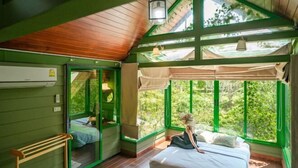 A bedroom with a large window, a bed, a bench, and a ceiling fan. - Naralin Khaoyai (Pak Chong)