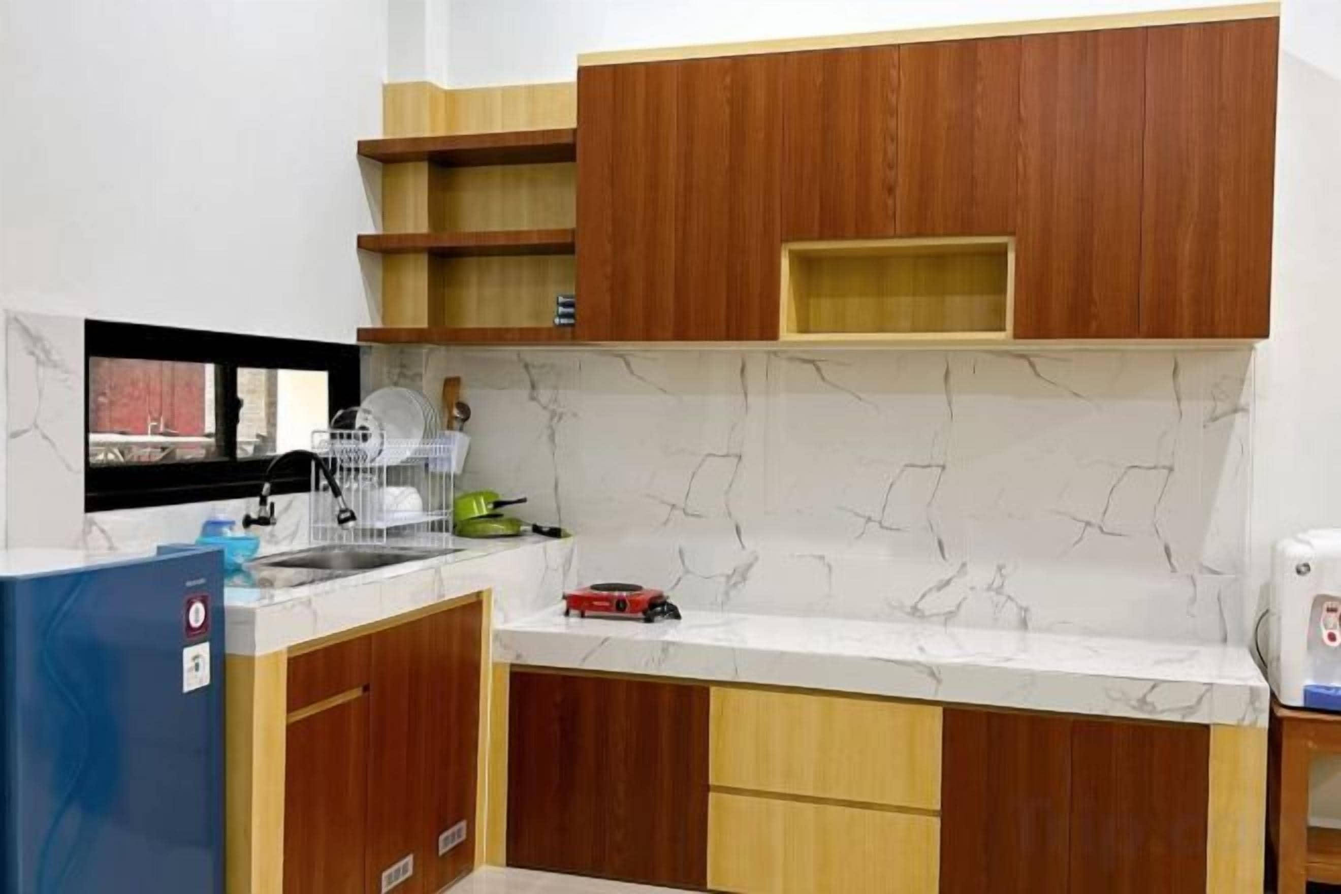 A kitchen with wooden cabinets, a marble backsplash, and a blue refrigerator.