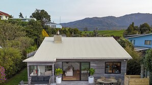 Une maison moderne dotée d’une grande terrasse, d’un coin repas et offrant une vue sur les montagnes.