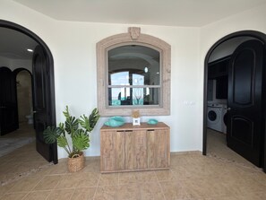 A hallway with a wooden cabinet, a mirror, and a potted plant.